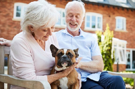 Uomo e donna che tengono il loro cane seduti su una panchina